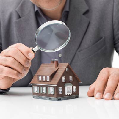 man holding magnifying glass over model home